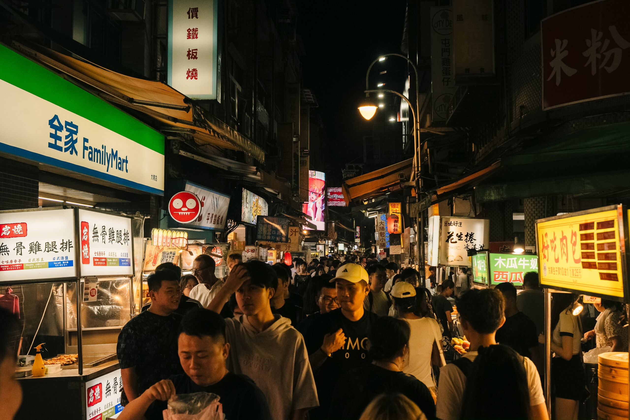 Night market in Taiwan with vibrant food stalls and bustling crowd, perfect for travel and food enthusiasts.