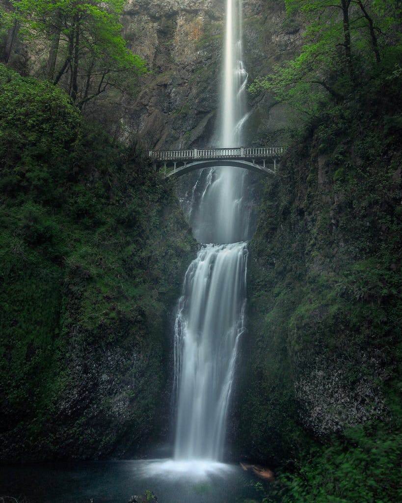 Stunning view of a cascading waterfall with a bridge in Oregon, perfect for nature enthusiasts.